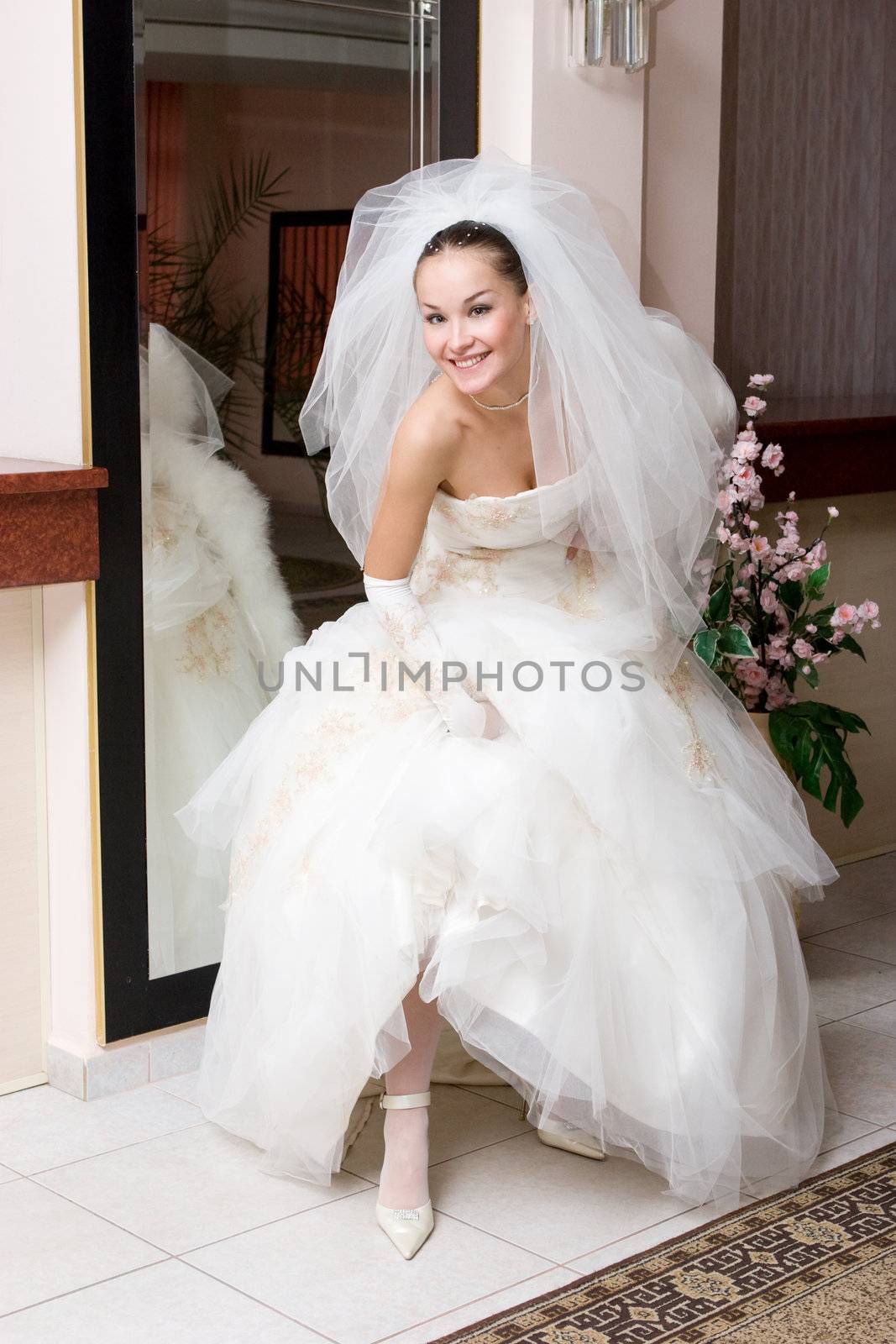 happy bride shows a shoe near the big mirror