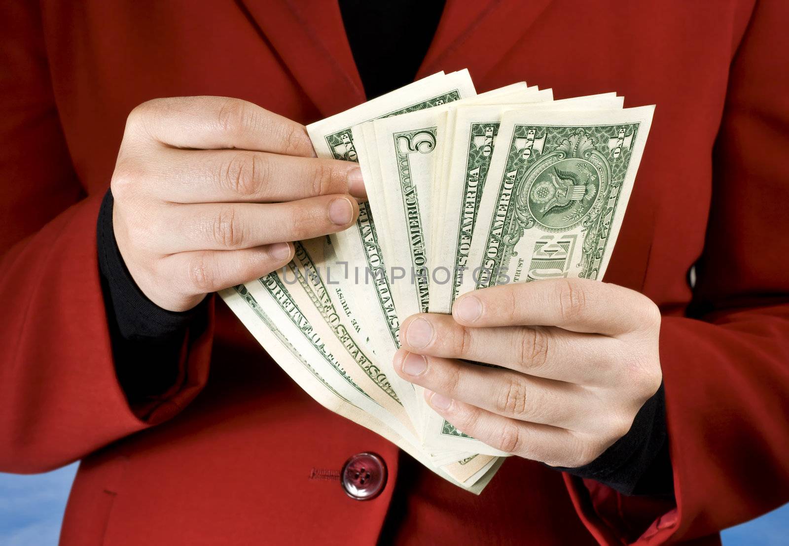 Female dressed in a red business dress using hands to count American dollars.

Studio shot.