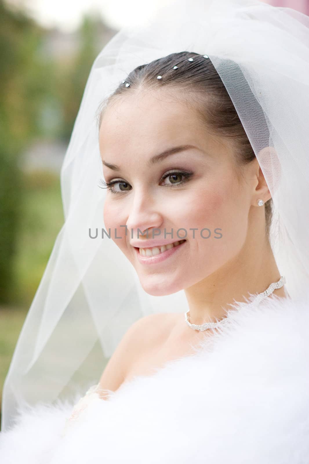 The beautiful smiling bride in a white fur cape