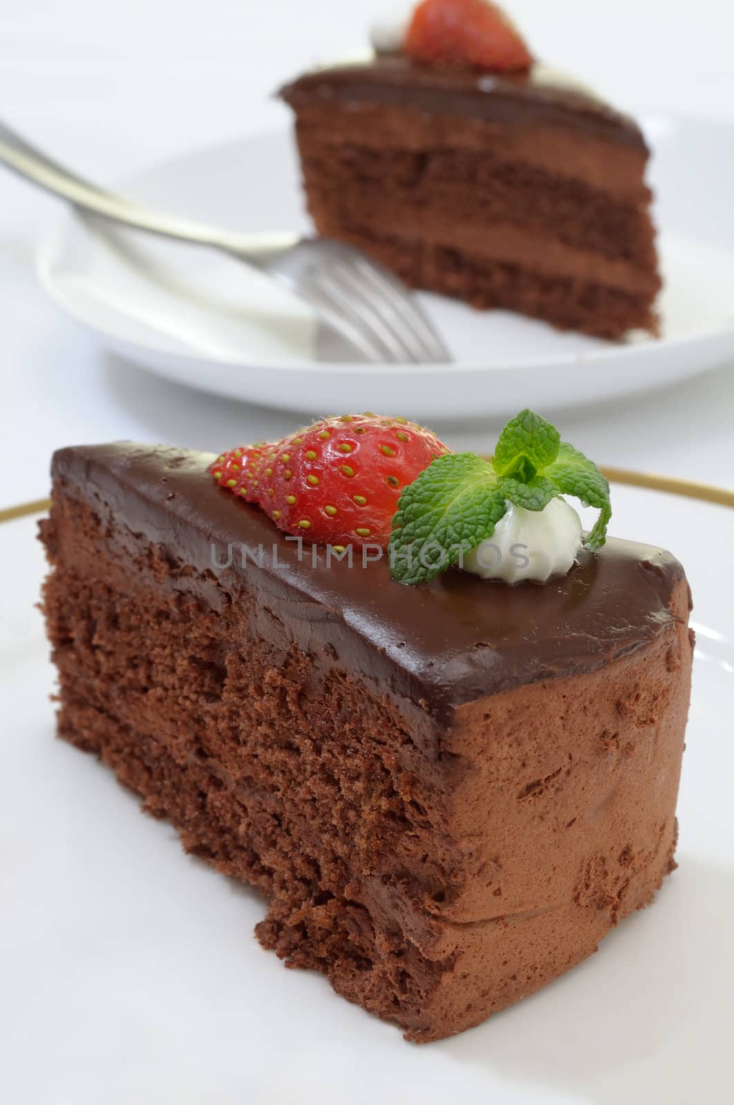 Chocolate cake slice decorated with a strawberry and mint leaves