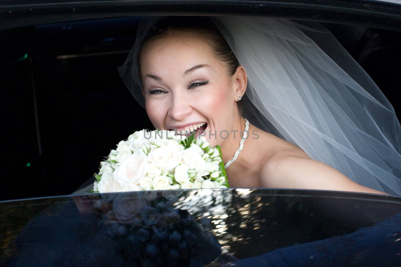 happy bride with flower bouquet in the wedding car