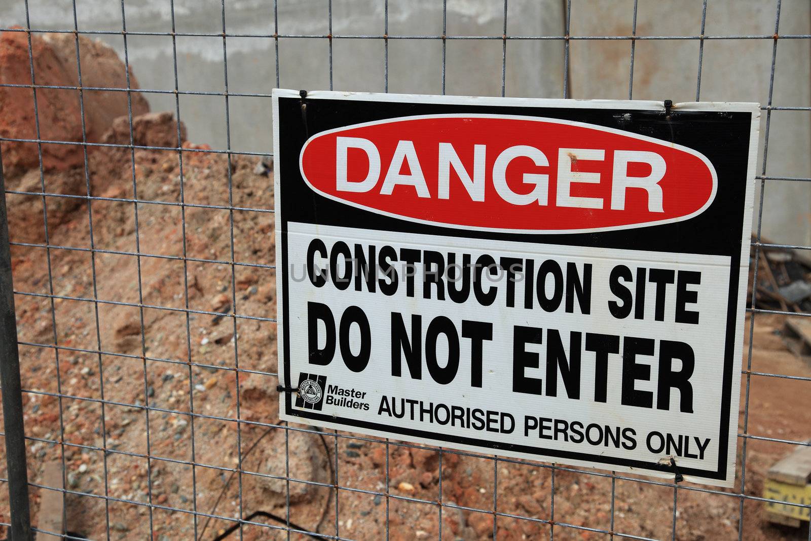 Warning sign on a construction site fence.