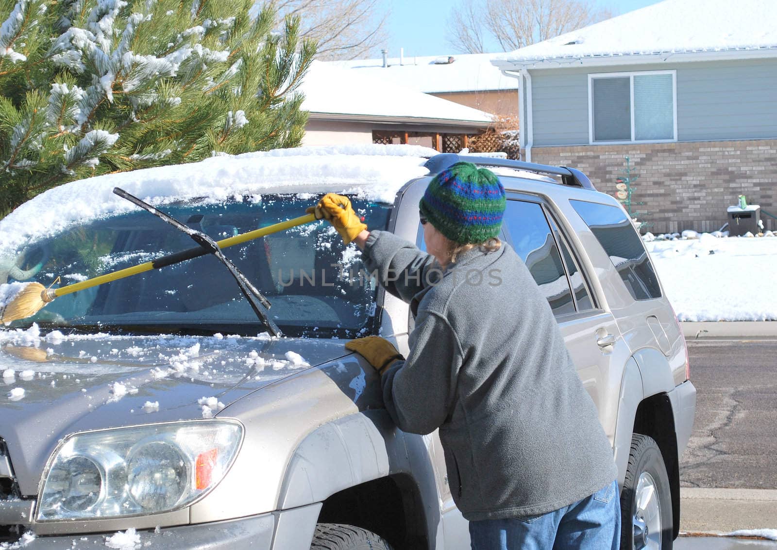 Female clearing snow off her suv.