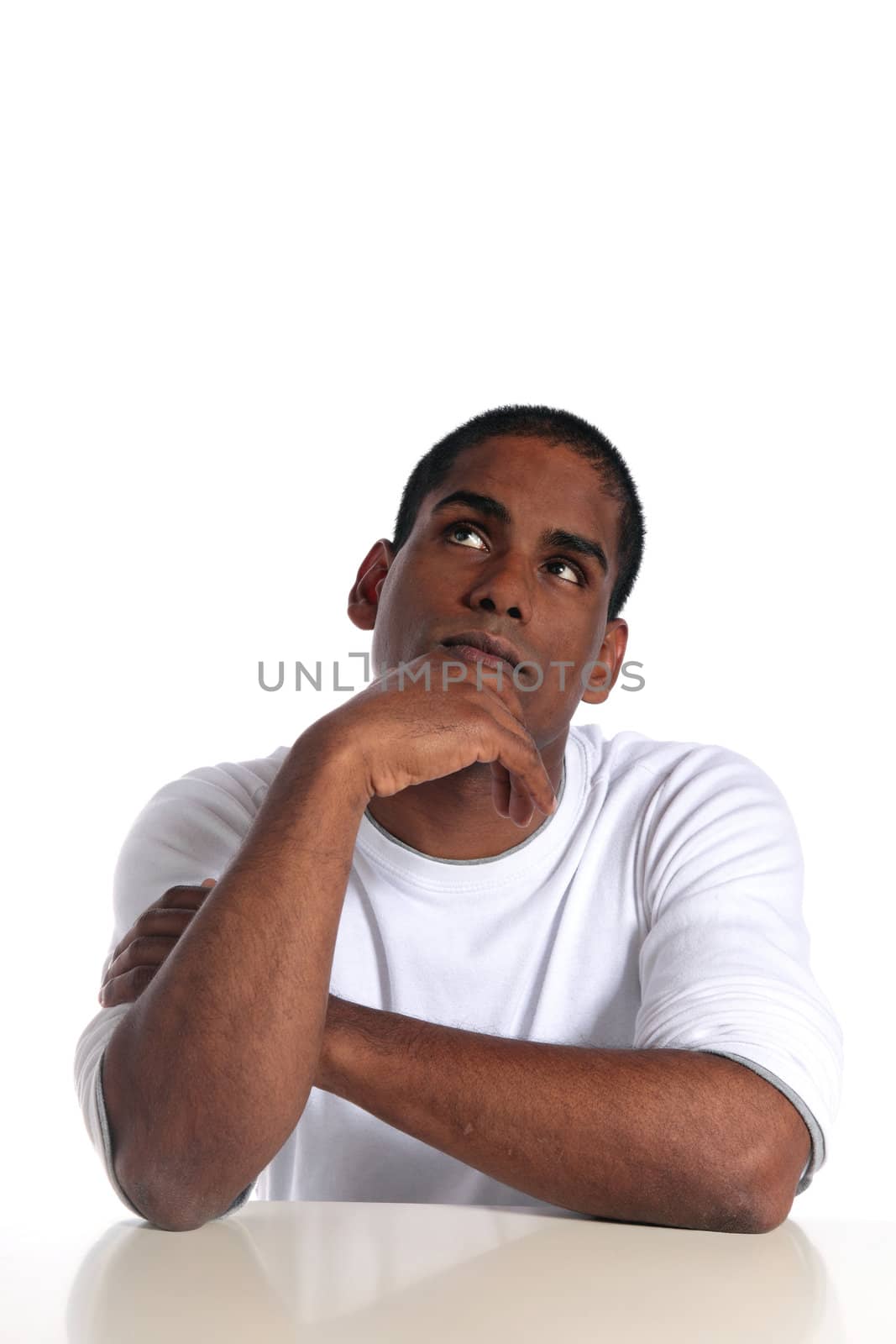 An attractive dark-skinned man deliberates a decision while sitting at a table. All on white background.