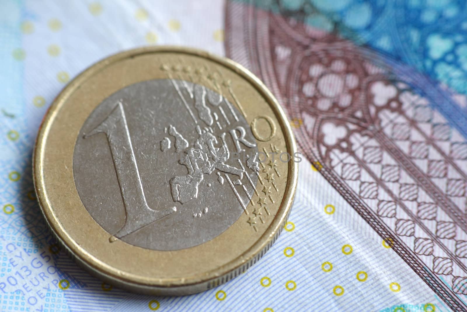 A single euro coin on a banknote.