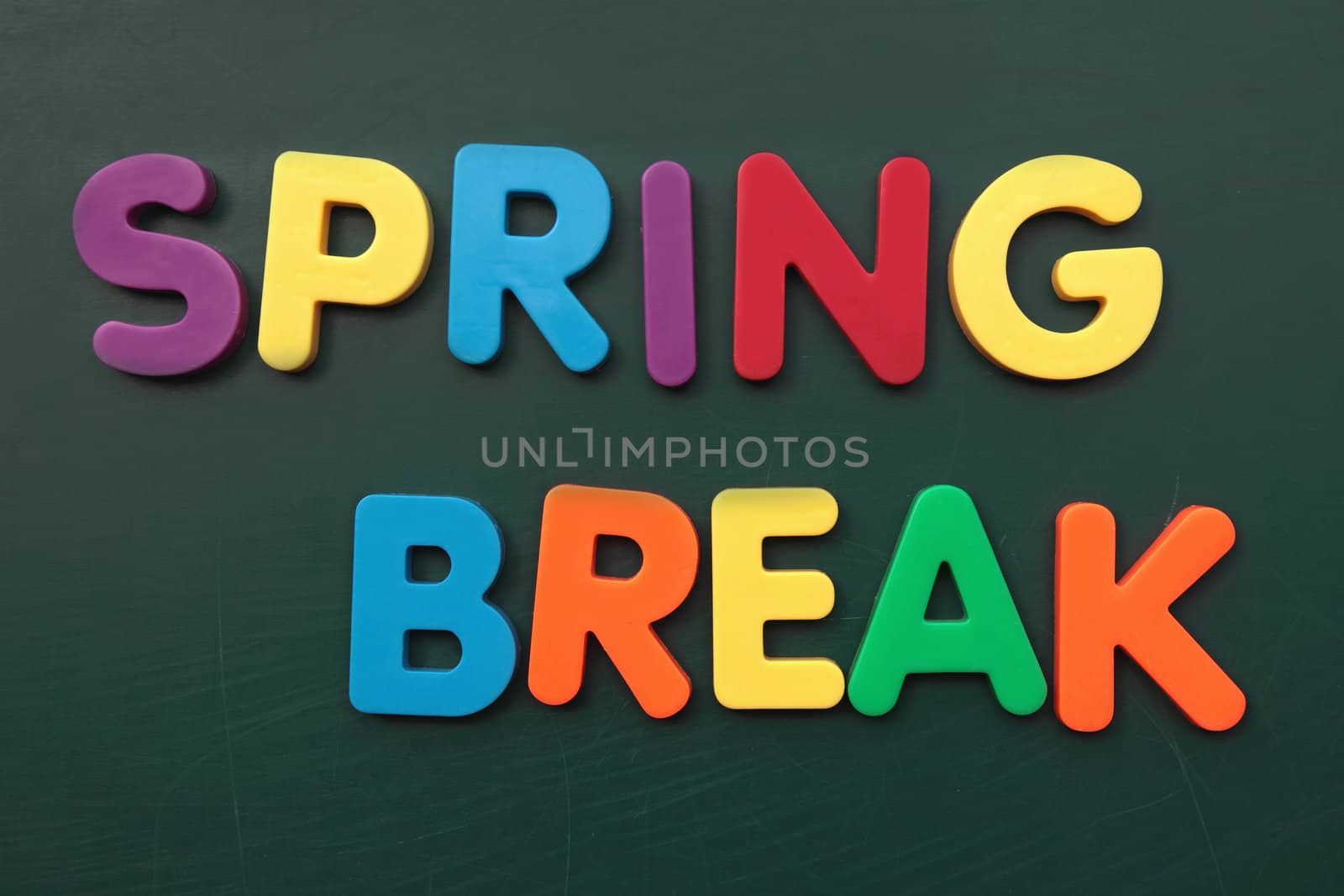 Several bold multicolored letters build the term spring break on a blackboard.