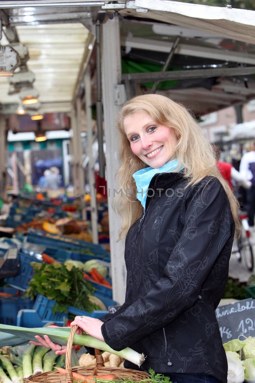 Young woman with a basket on the market.she stands at the market stall and smiles