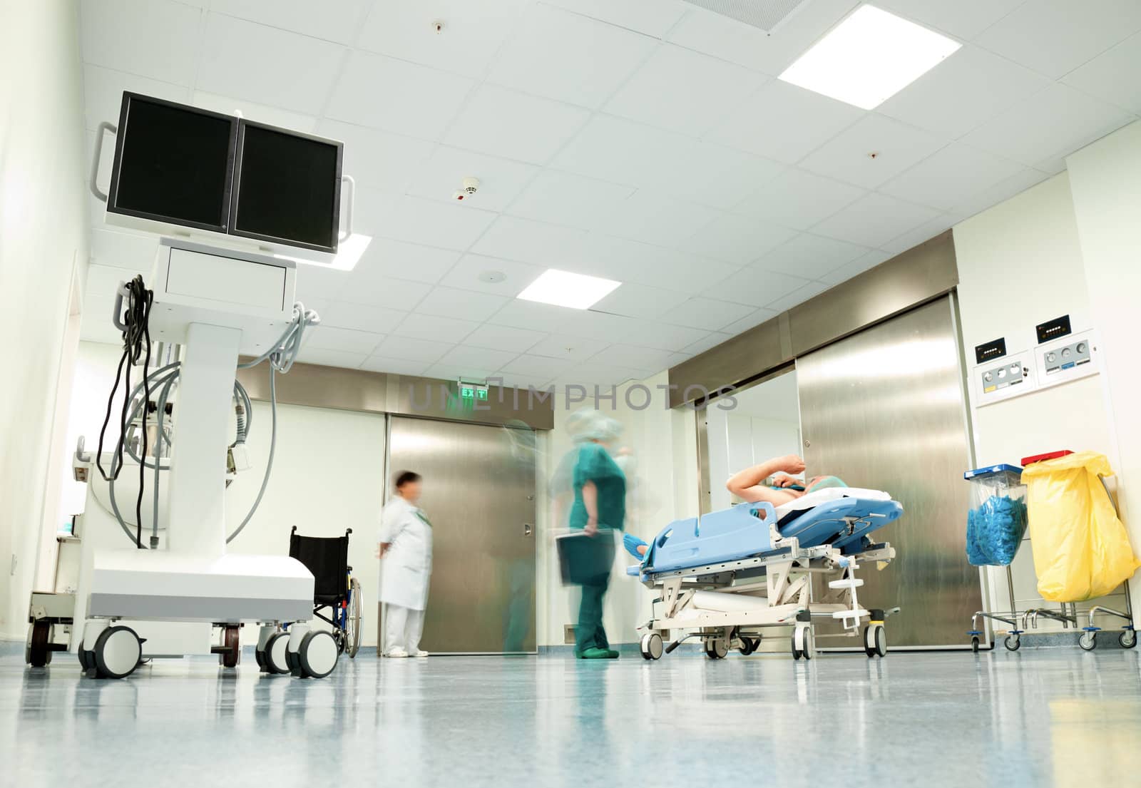 Blurred figures with medical uniforms moving patient in hospital corridor