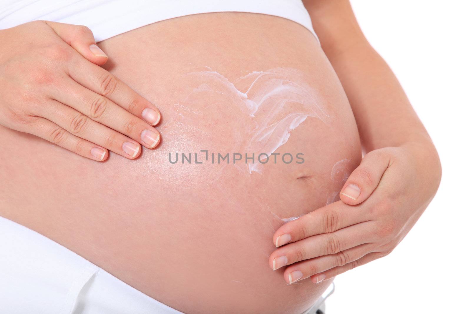 Pregnant woman puts lotion on her baby bump. All on white background.