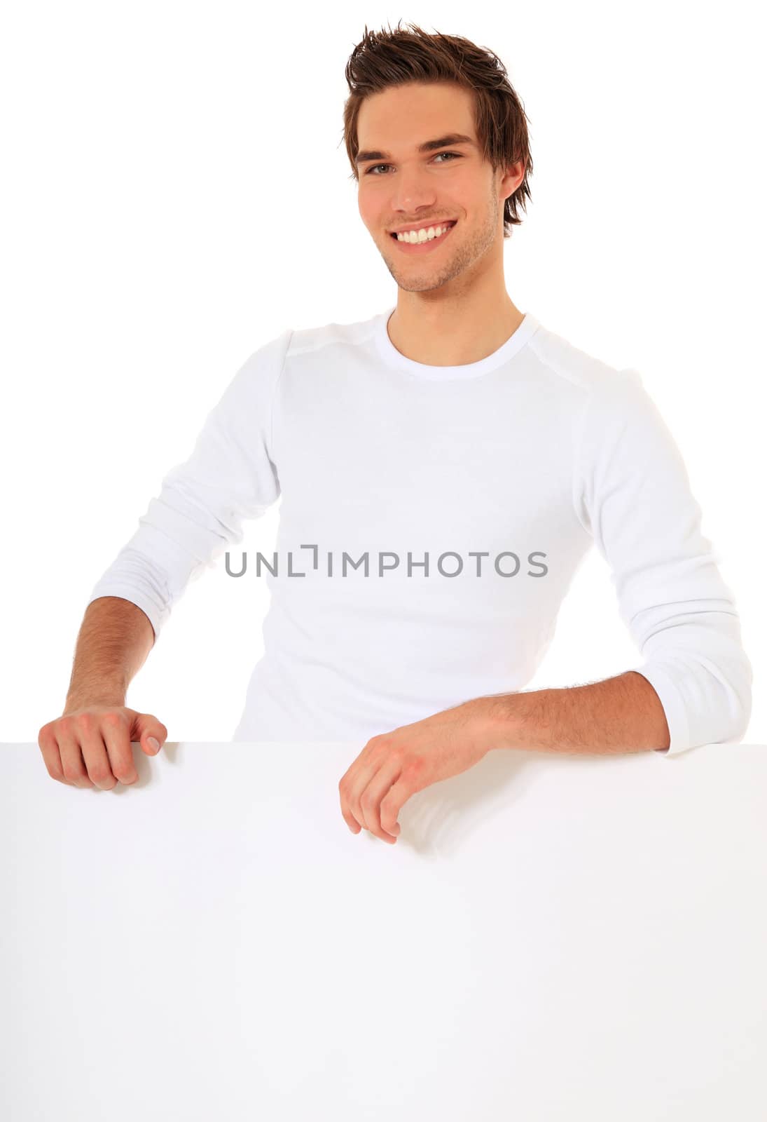 Attractive young man standing behind white wall. All on white background.