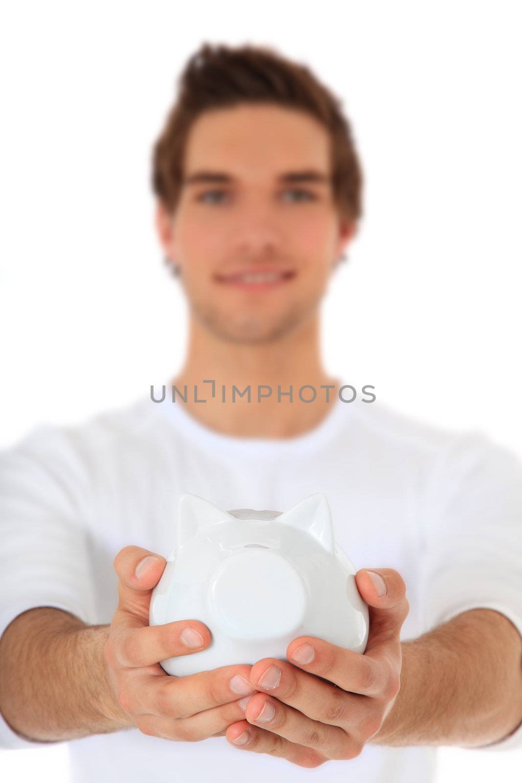 Attractive young man holding piggy bank. Selective focus on piggy bank. All on white background.