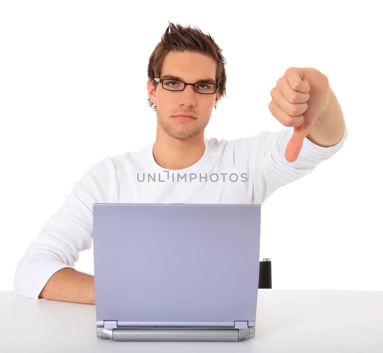 Young guy showing thumbs down while using notebook computer. All on white background.