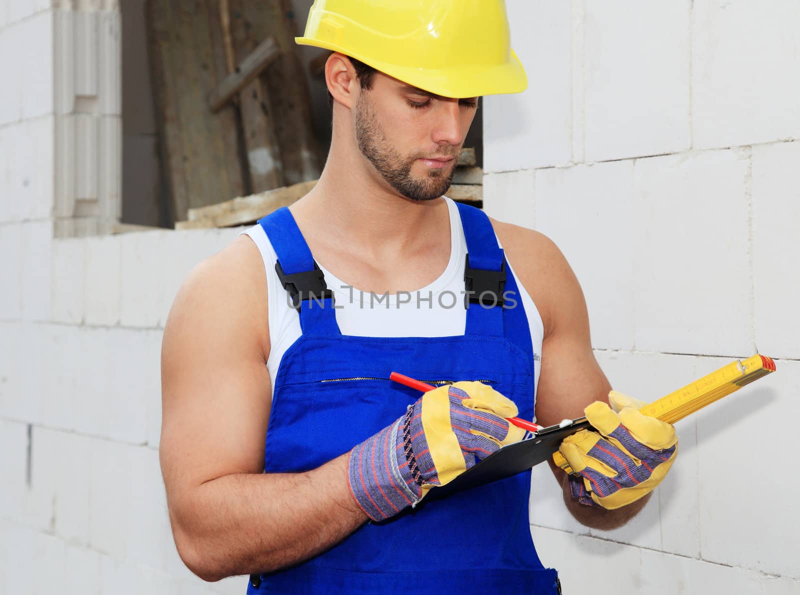 Manual worker on construction site writing on clipboard.