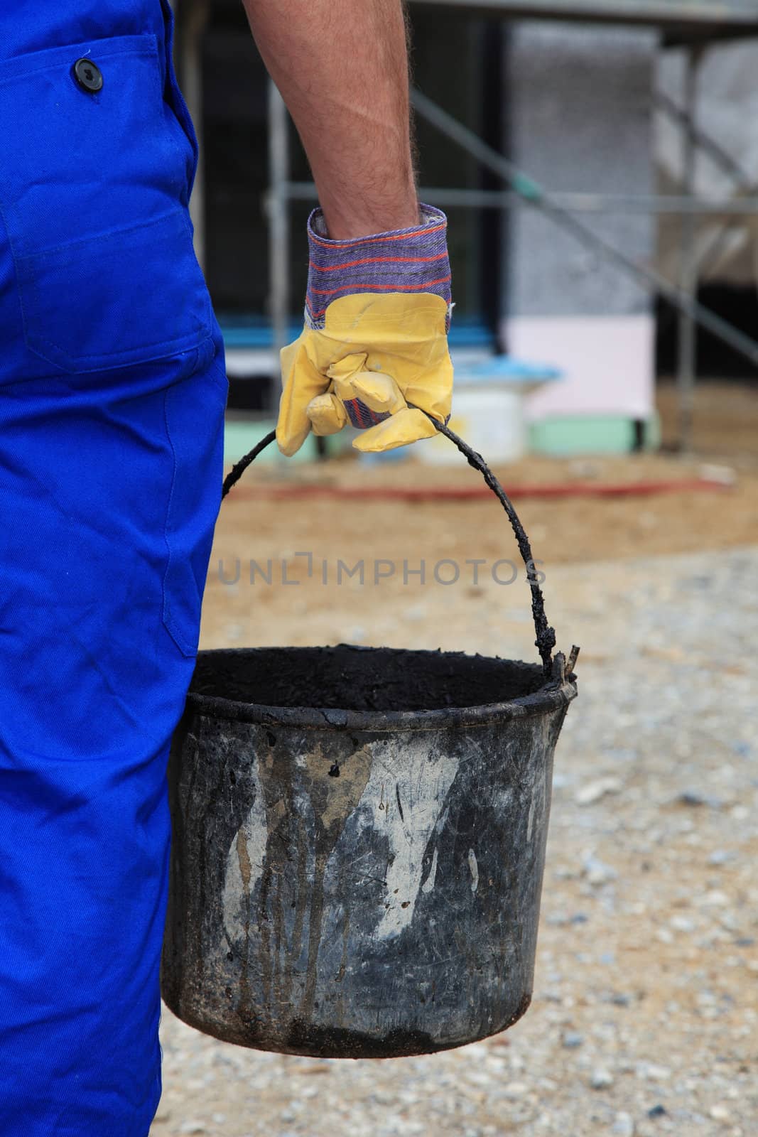 Manual worker carrying a bucket.