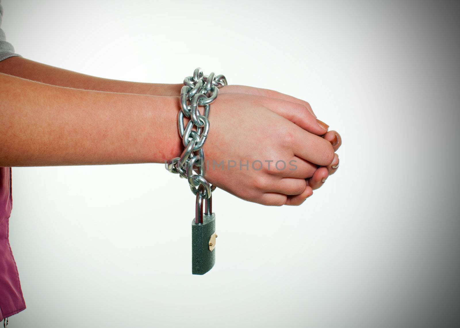 Hands tied up with chains against light background