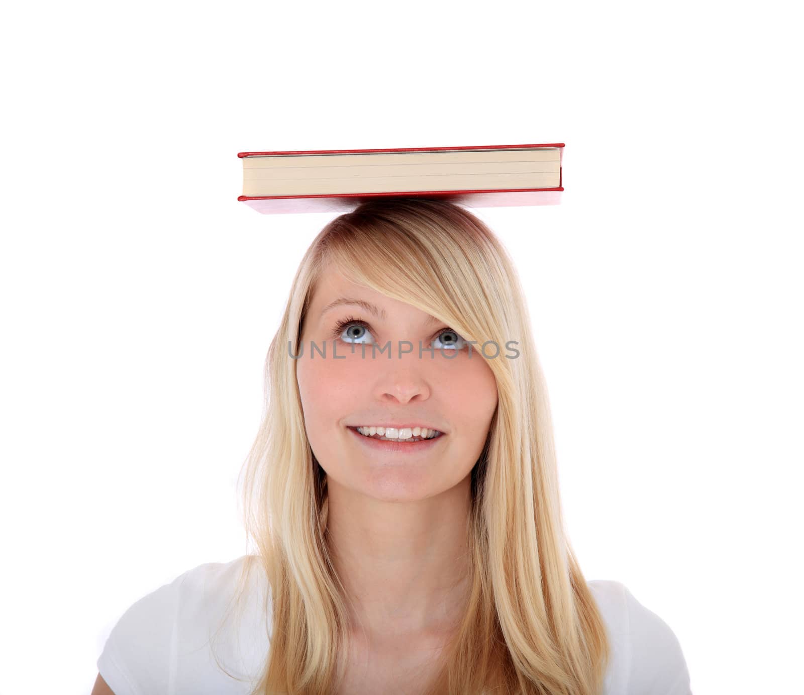 Attractive teenage girl balancing a book on her head. All on white background.