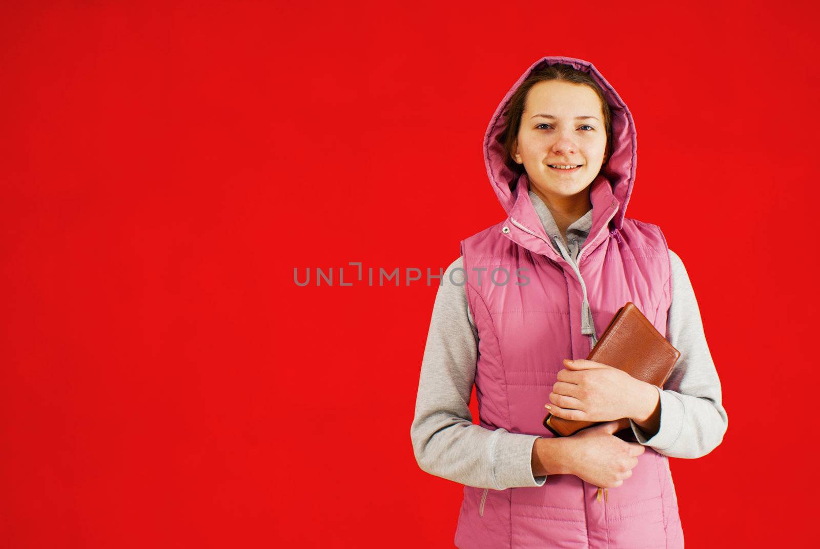 Teen girl staying with a book against red background