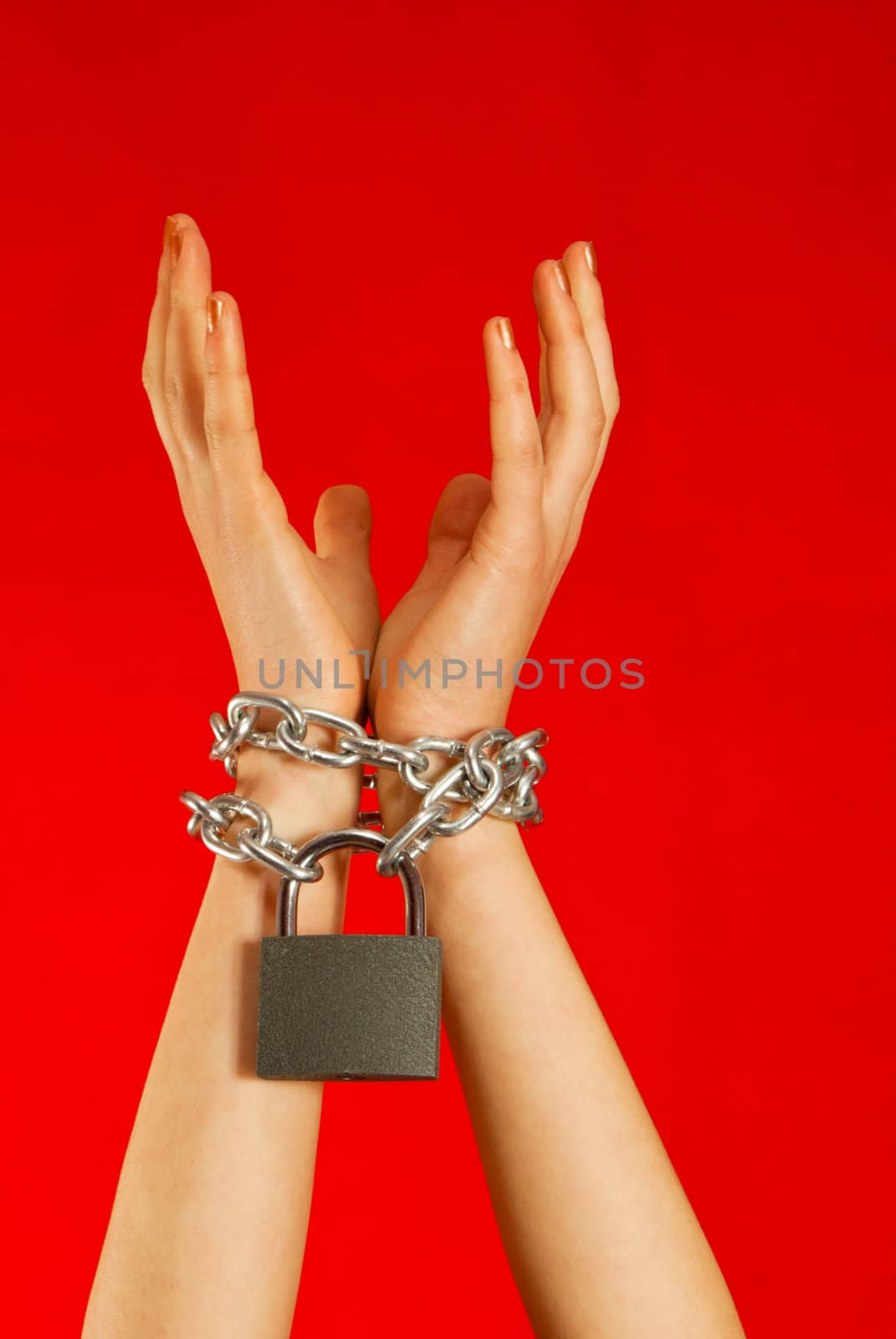 Hands tied up with chains against red background
