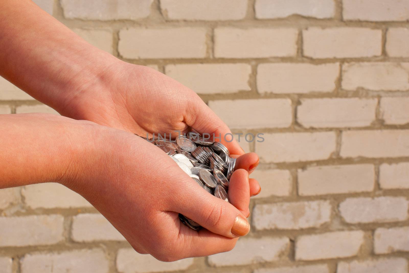 Palms full of coins against brick wall