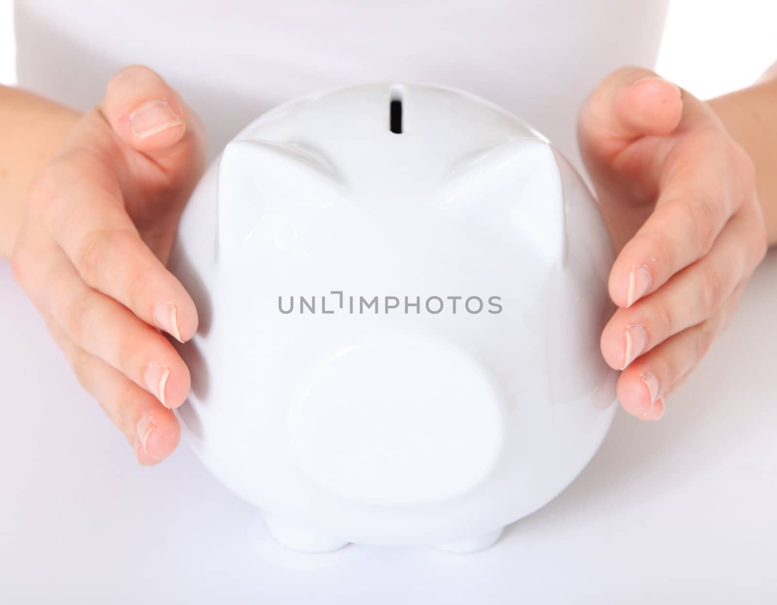 Human hands holding piggy bank. All on white background. Selective focus on piggy bank in foreground.