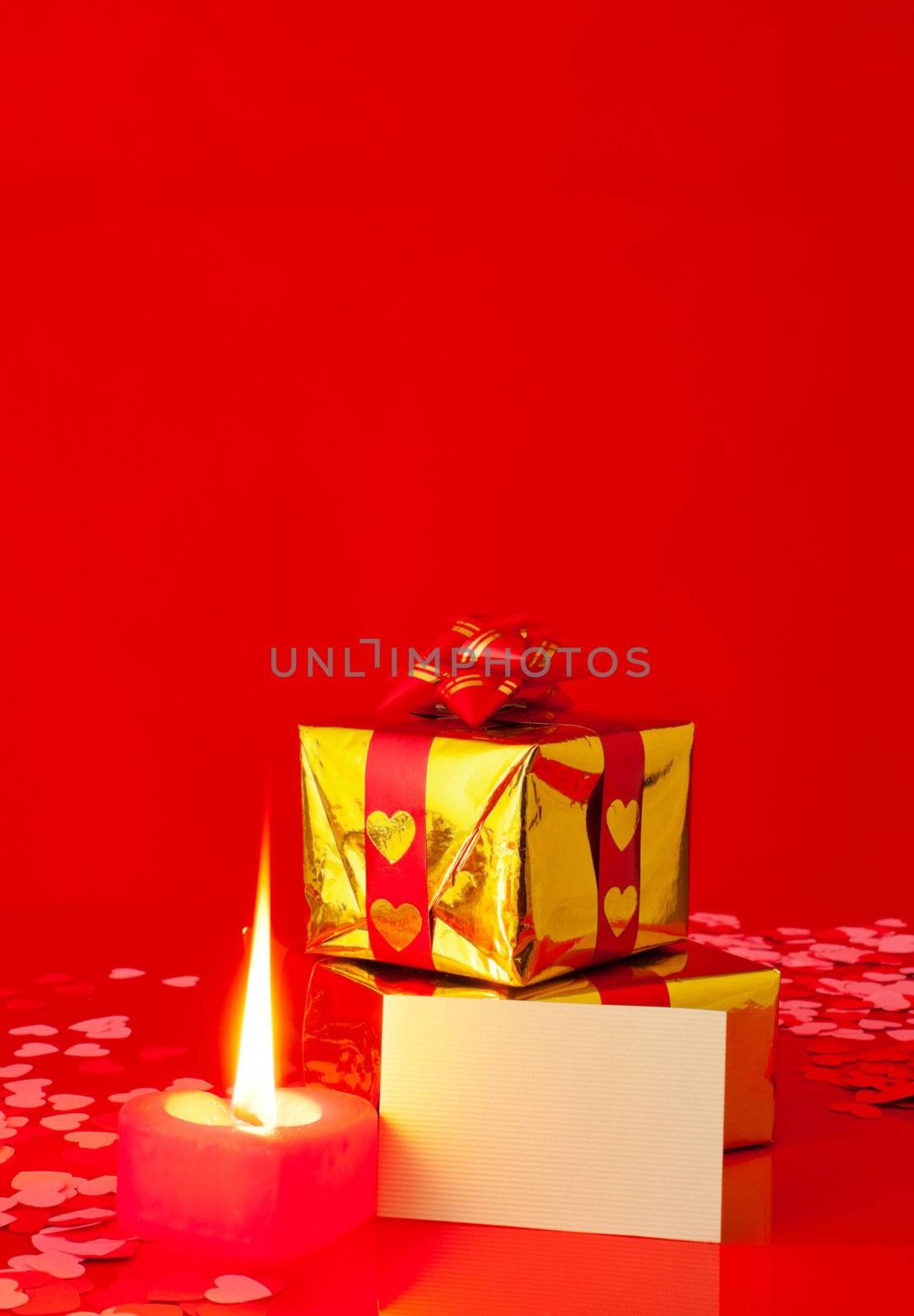 Presents and burning heart shaped candle with blank card