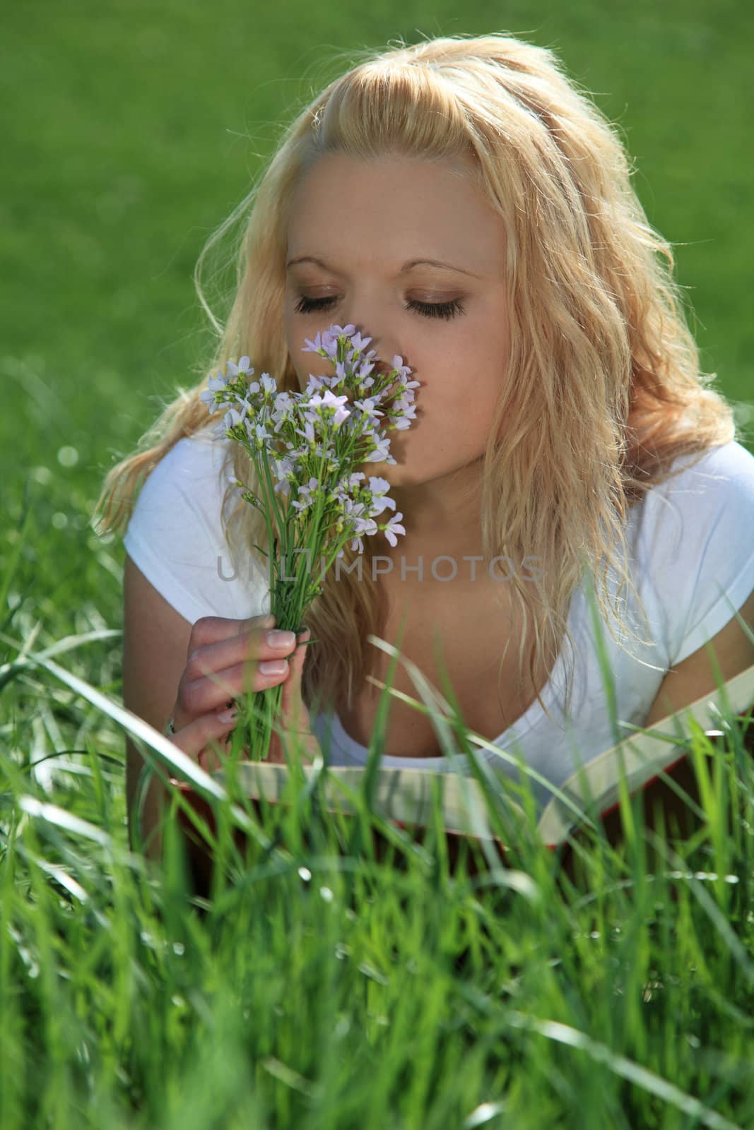 Attractive young woman resting outside on green meadow.
