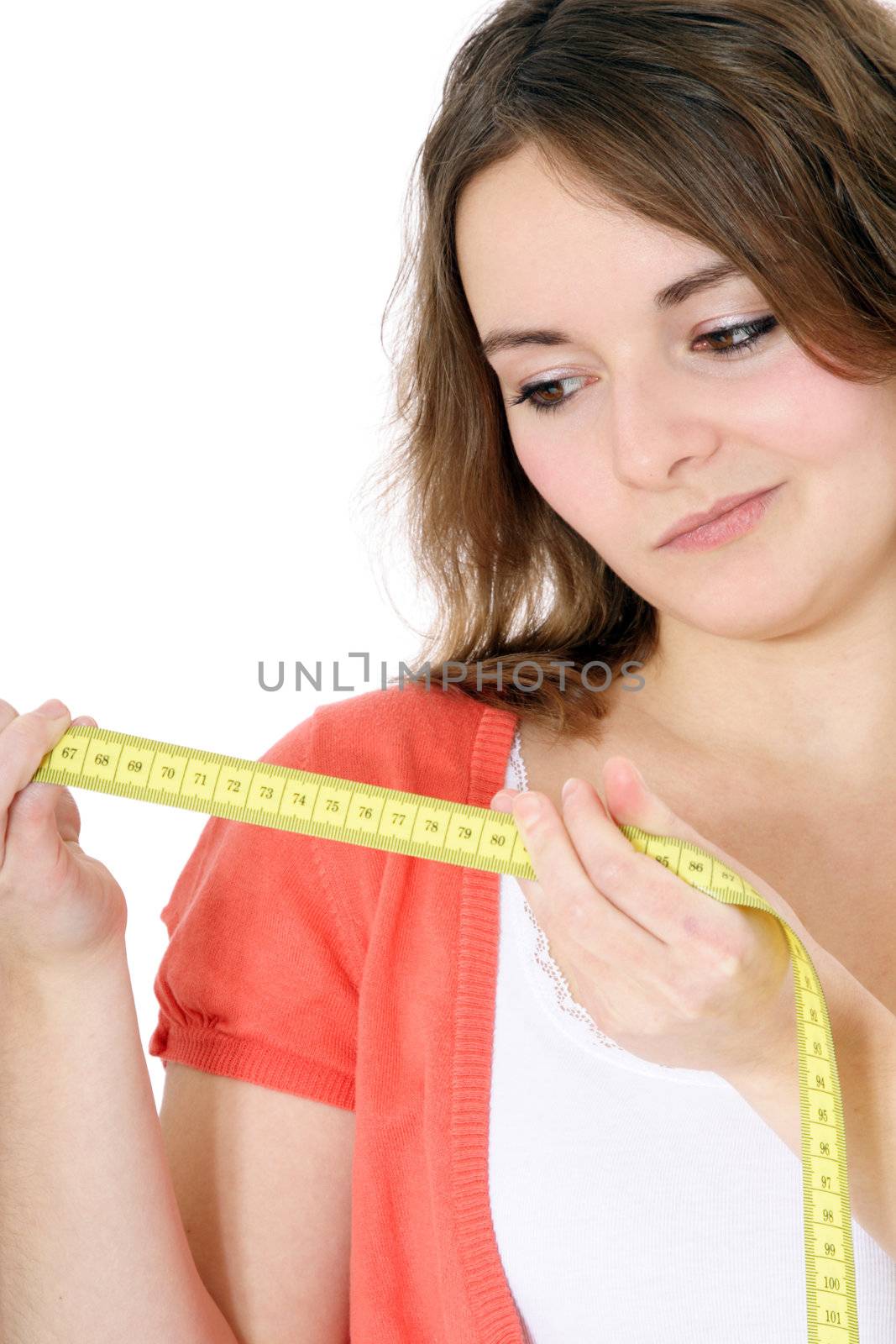 Attractive young woman looking at measuring tape. All on white background.
