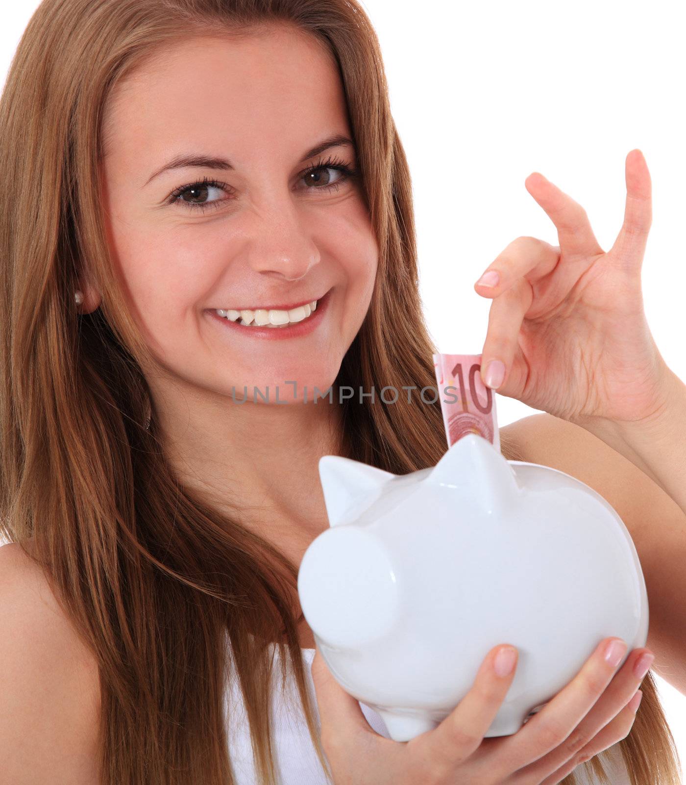 Attractive brunette girl puts money in her piggy bank. All on white background.