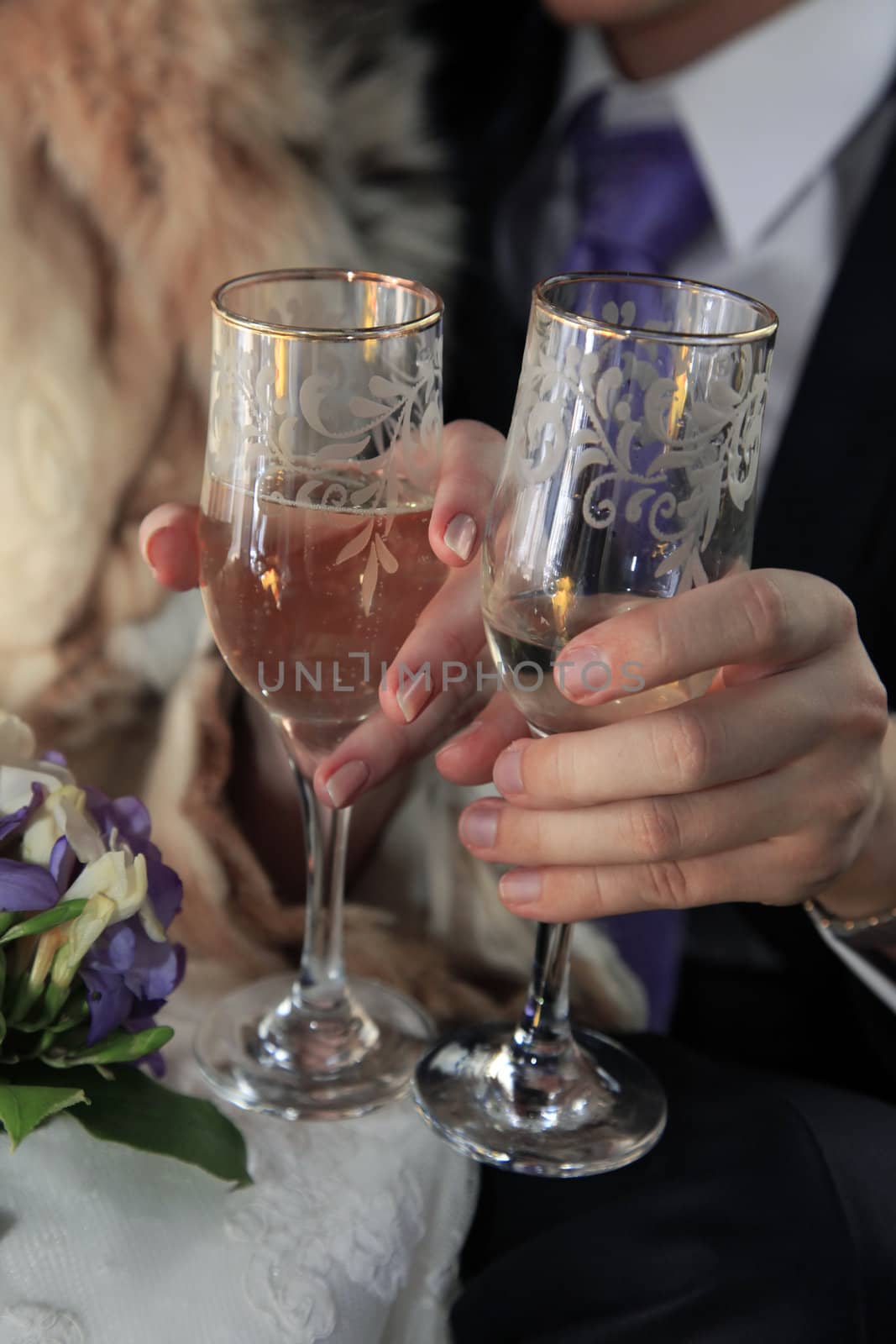 Glass of champagne in a hands of the groom and bride