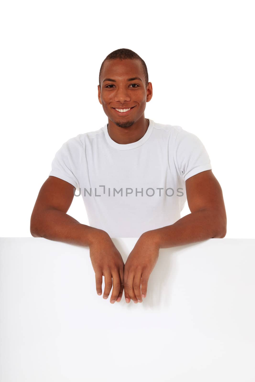 Attractive black man standing behind white wall. All on white background.