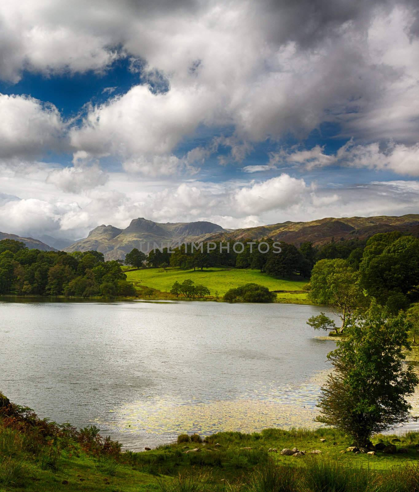 Sun illuminating Langdale Pikes with Loughrigg Tarn in foreground
