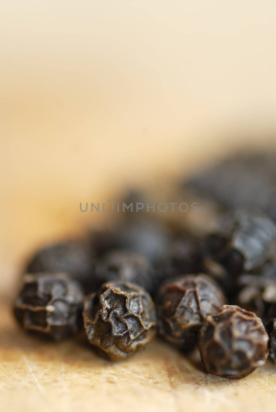 Macro image of pepper corns on a wooden chopping board.