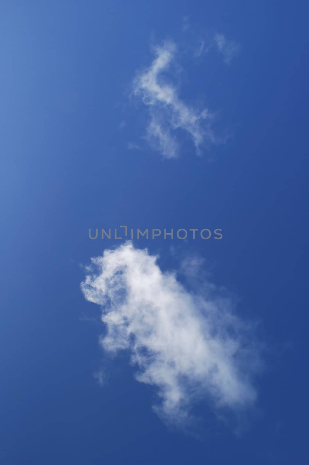 Simple composition of a blue sky and two white wispy clouds.
