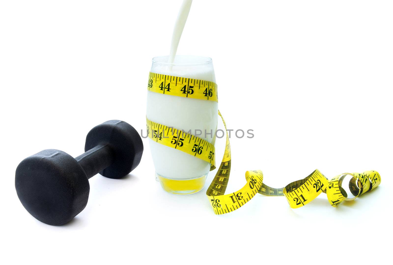 Glass of protein rich milk with an exercise dumbbell and measuring tape 