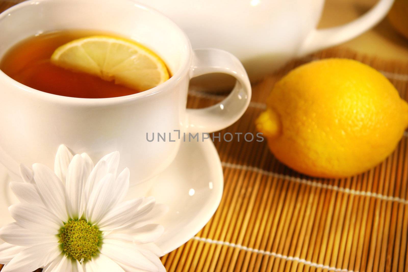 Tea cup  and teapot with lemon and daisy on the table