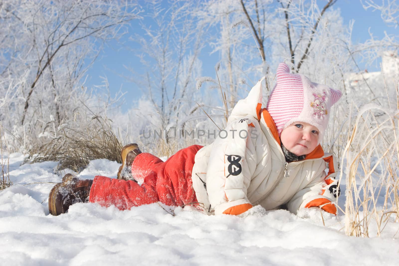 happy child lays on white snow