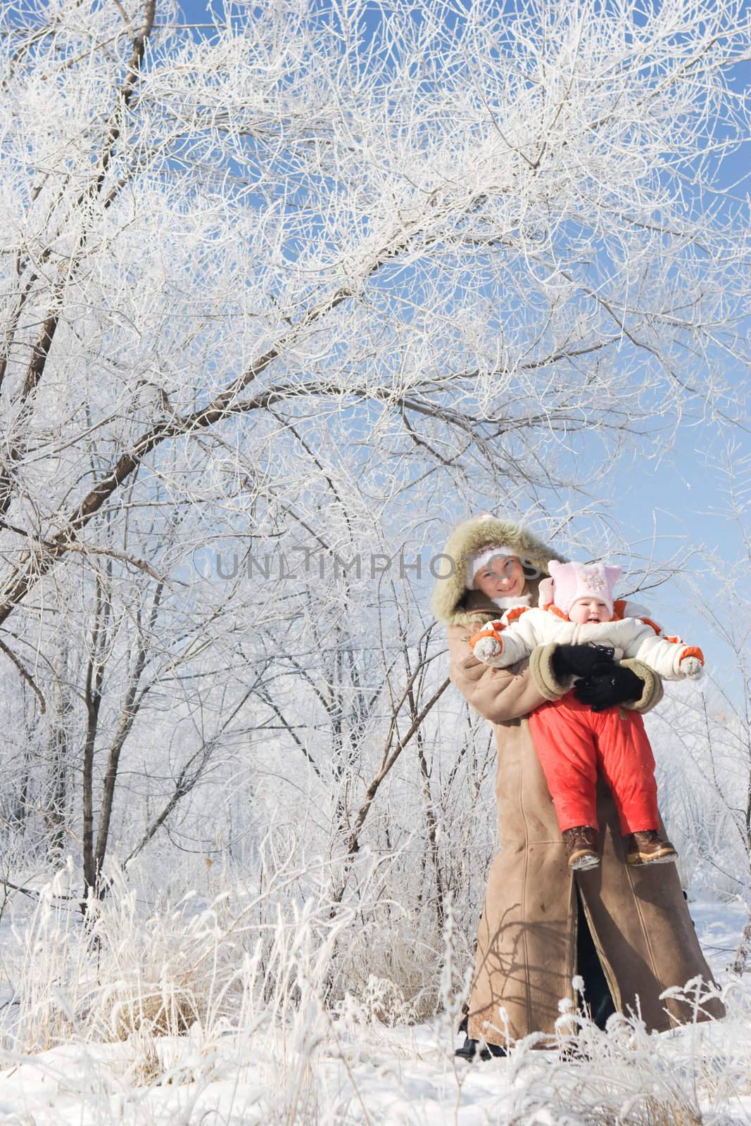 mother plays with her child in a winter forest by vsurkov
