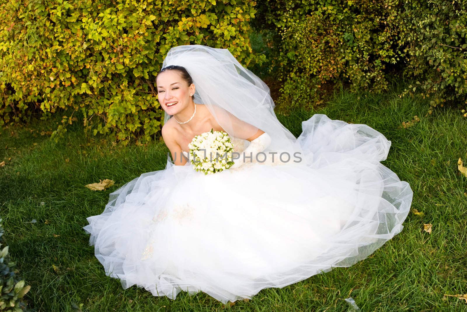happy bride with flower bouquet seating in the meadow