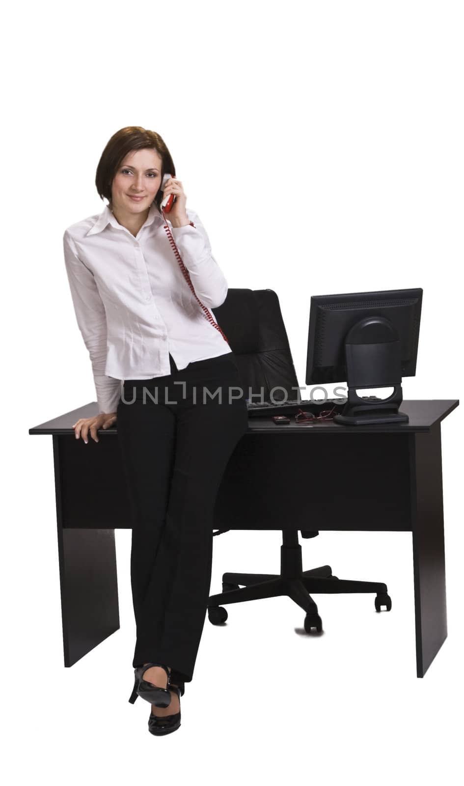 Young businesswoman on the phone leaning against her desk, isolated against a white background.