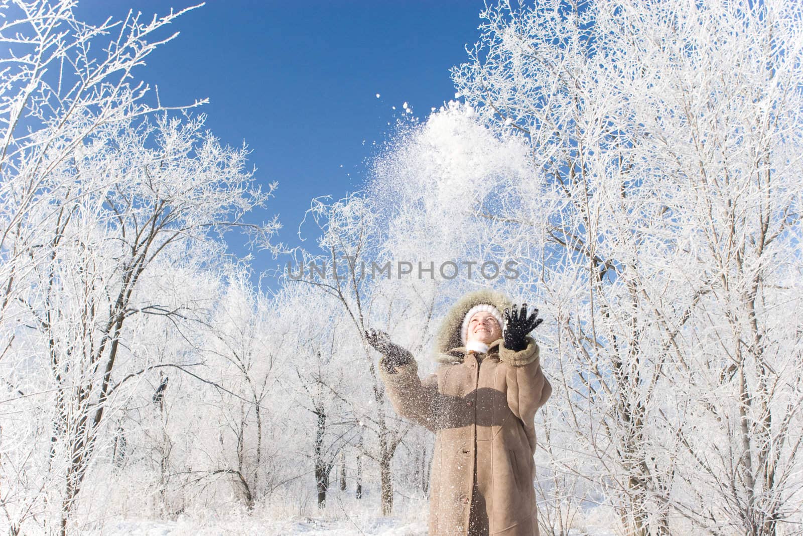 a girl throwing up snow in the winter forest