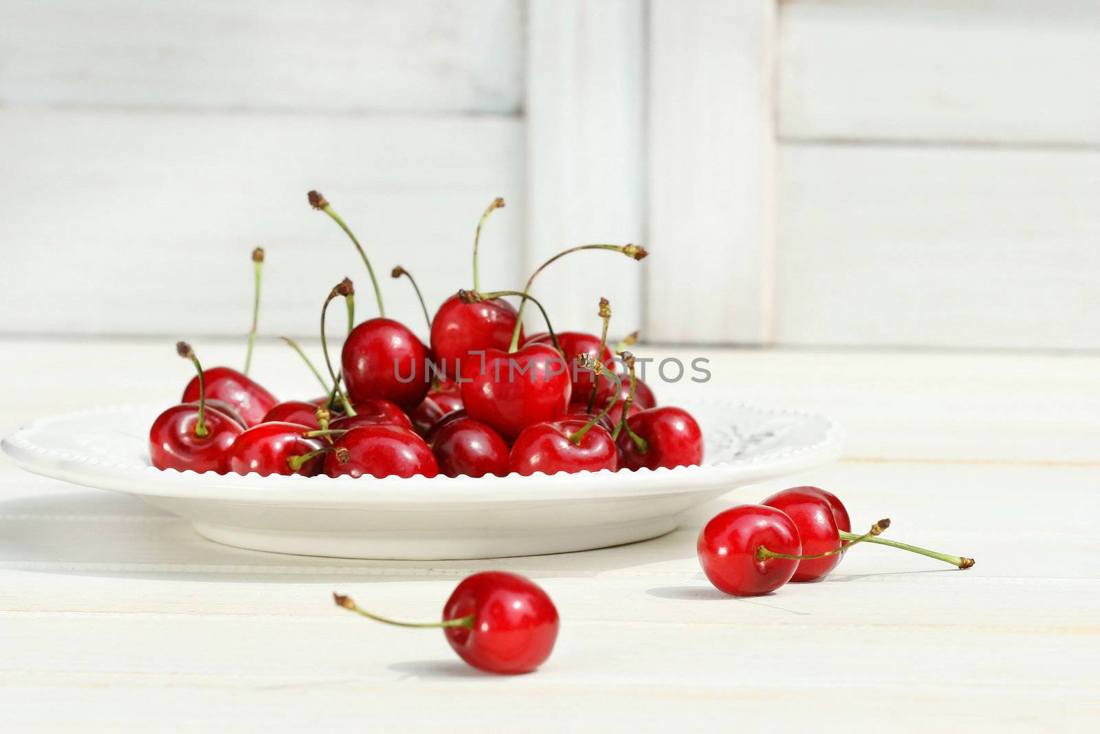 Cherries on a white plate by Sandralise
