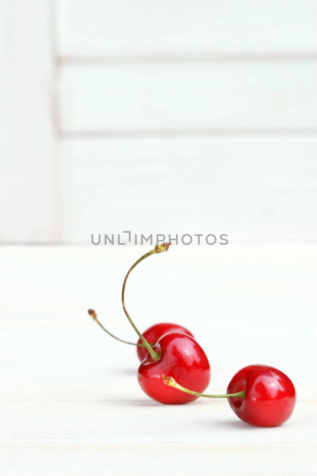 Three little cherries on white background