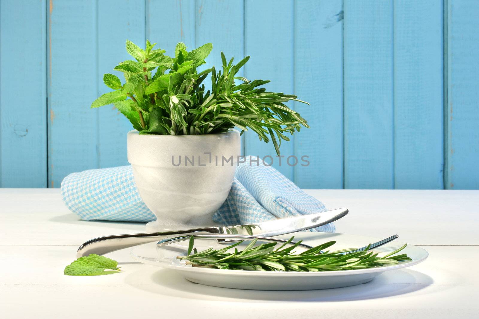 Fresh herbs on the table with plate and utensils 