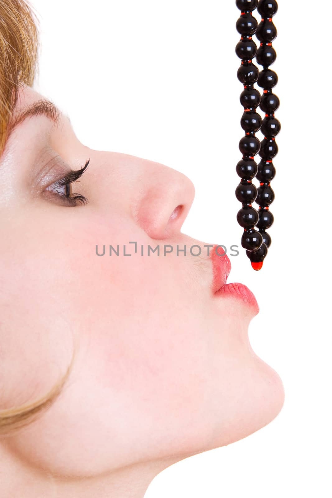 The girl catches with lips a drop of wine on beads