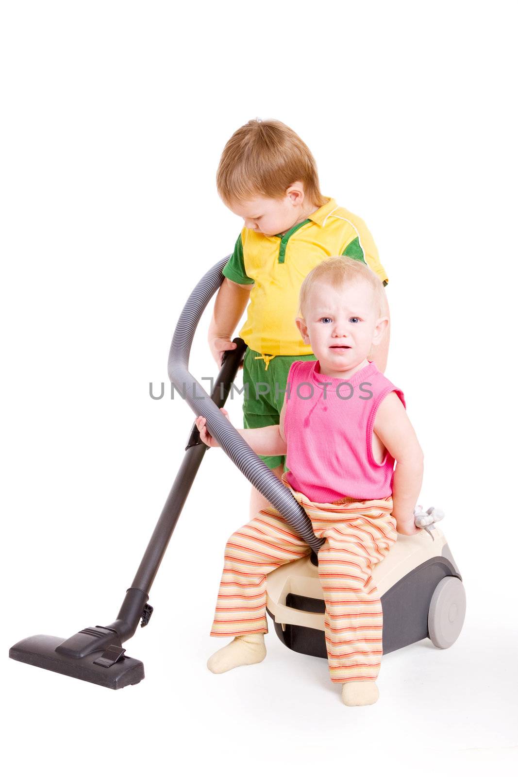 a small girl sitting on Vacuum cleaner and a small boy going in for cleaning