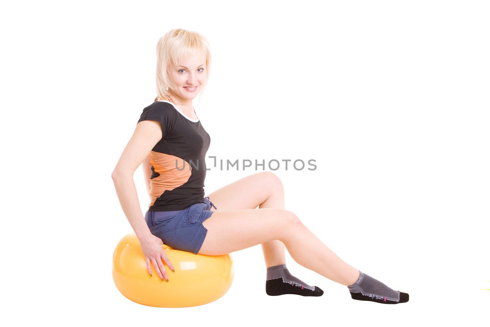 a young blond girl sitting on the big ball for fitness