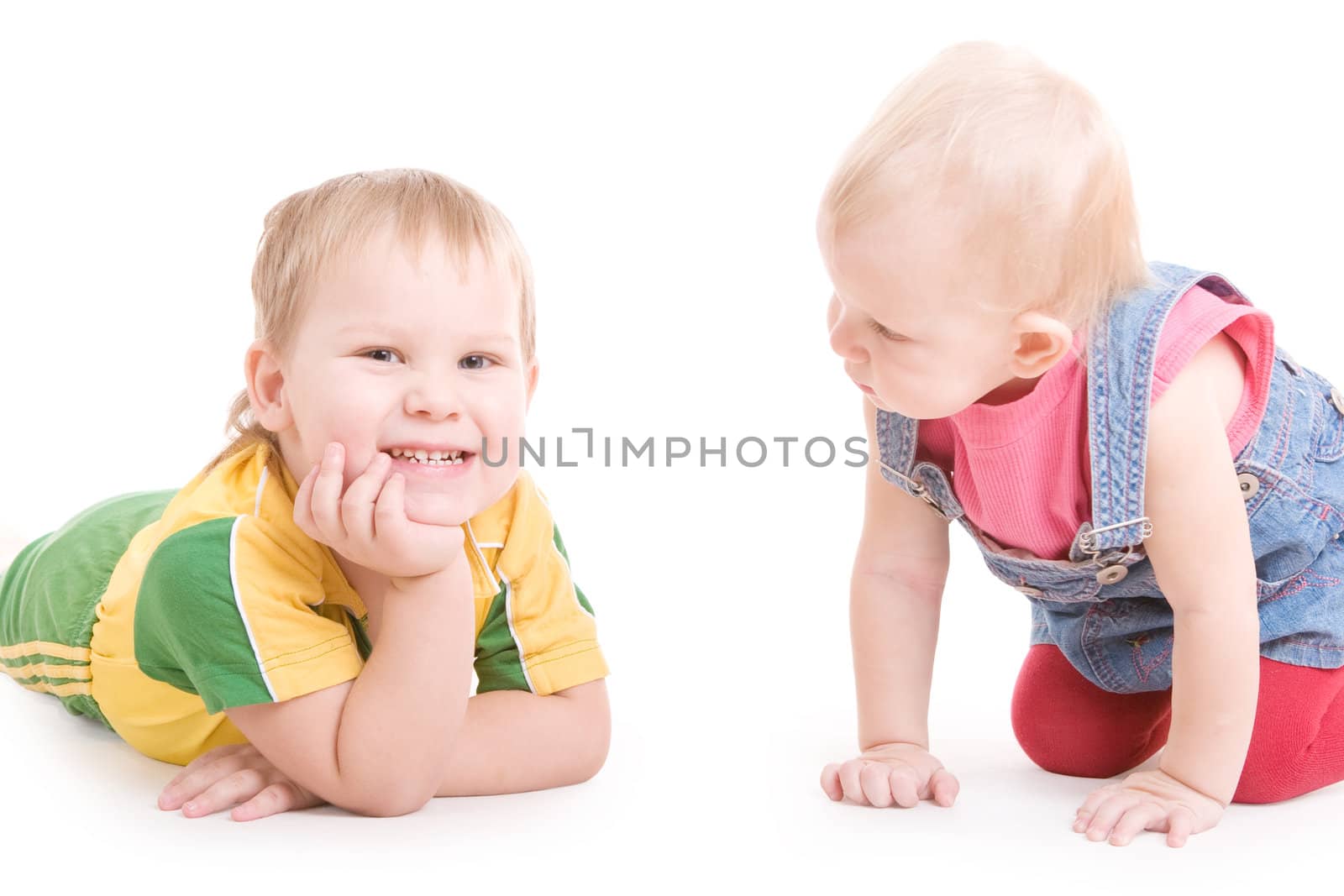 a small girl looking at the smiling boy, the both are on the floor