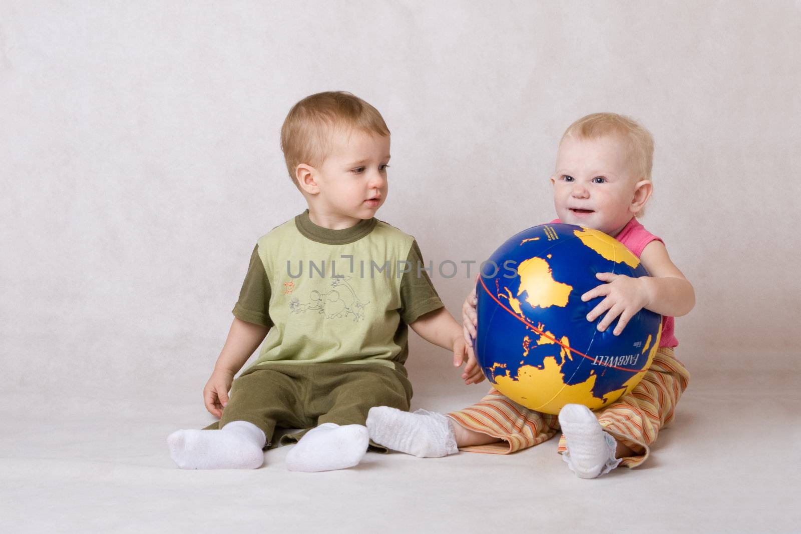 boy and the girl sit on a floor and play with ball