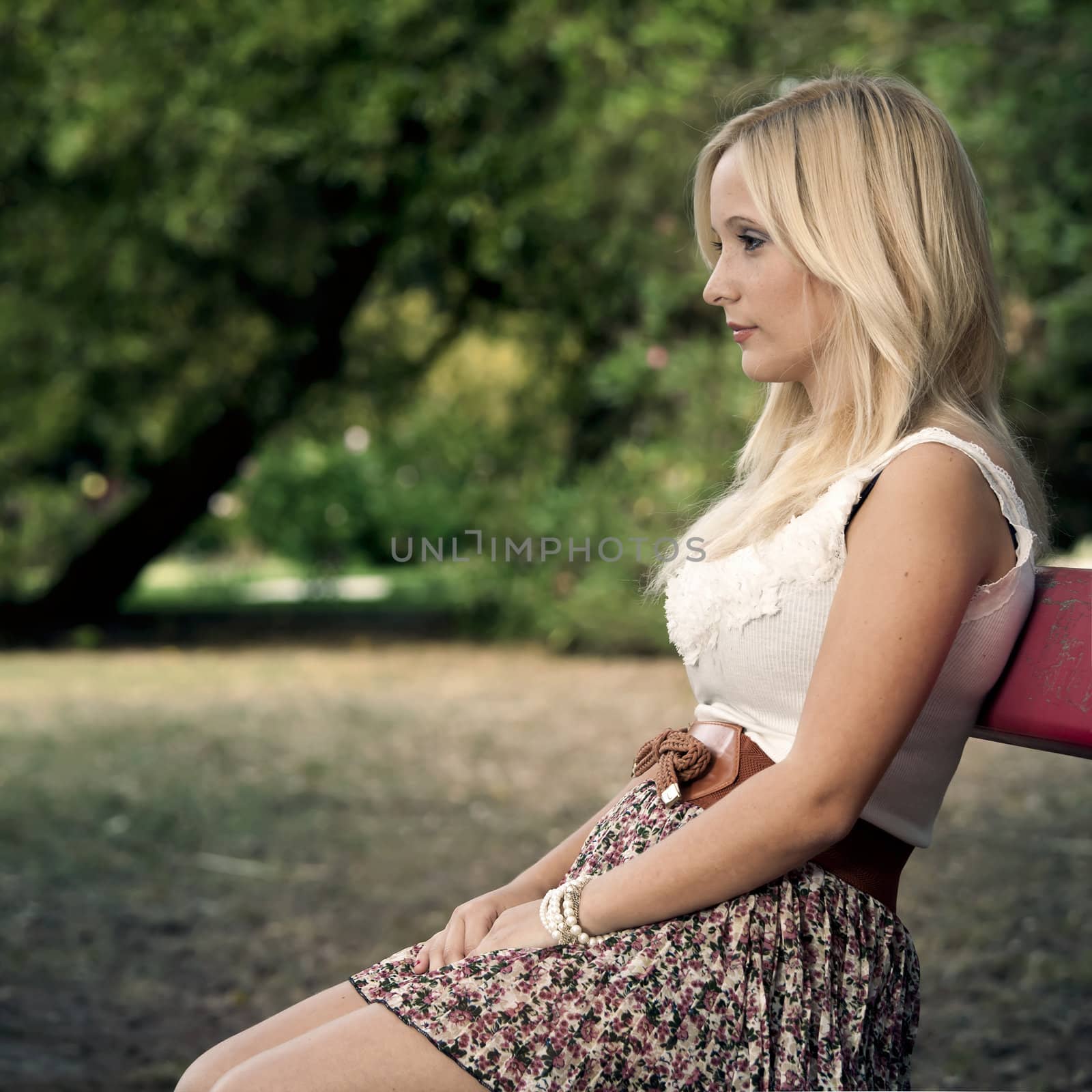 Beautiful young woman sitting on a park bench  and thinking on something