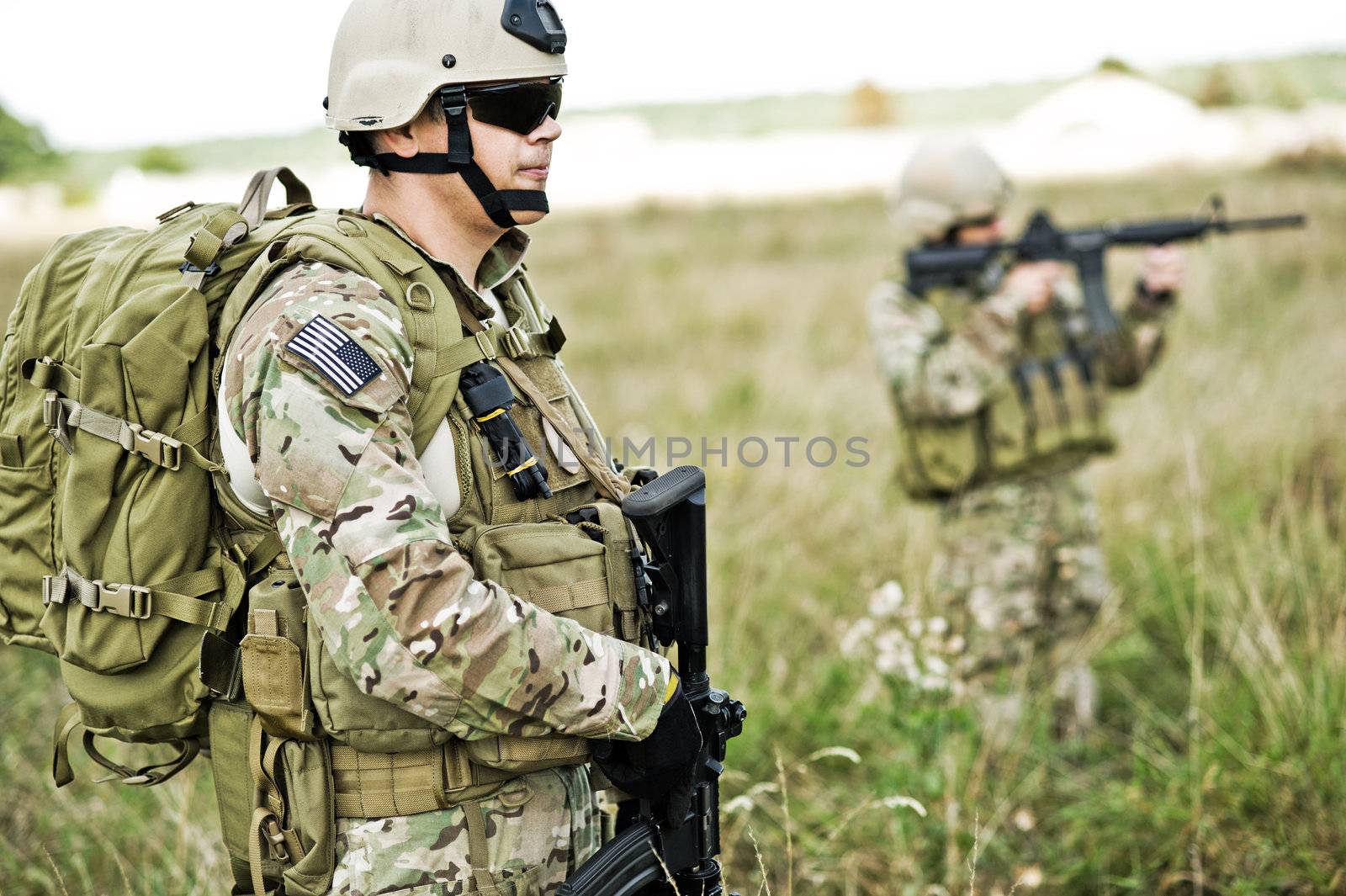 Soldiers  in full gear patrol the area in the desert